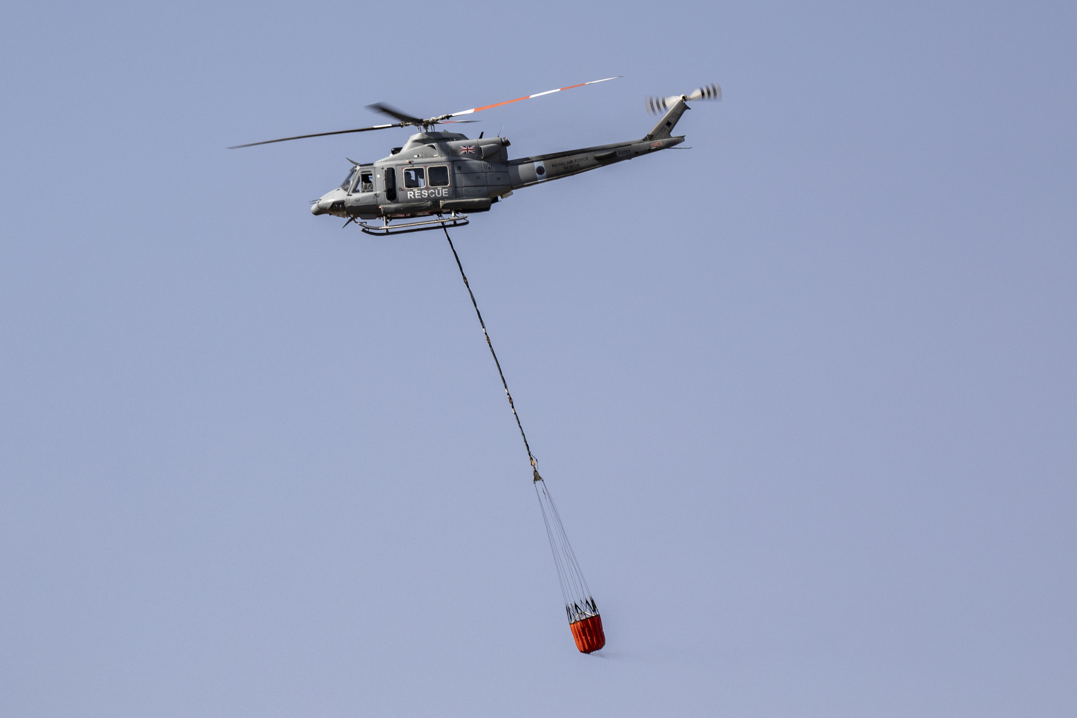 Image shows helicopter dropping water from under sling